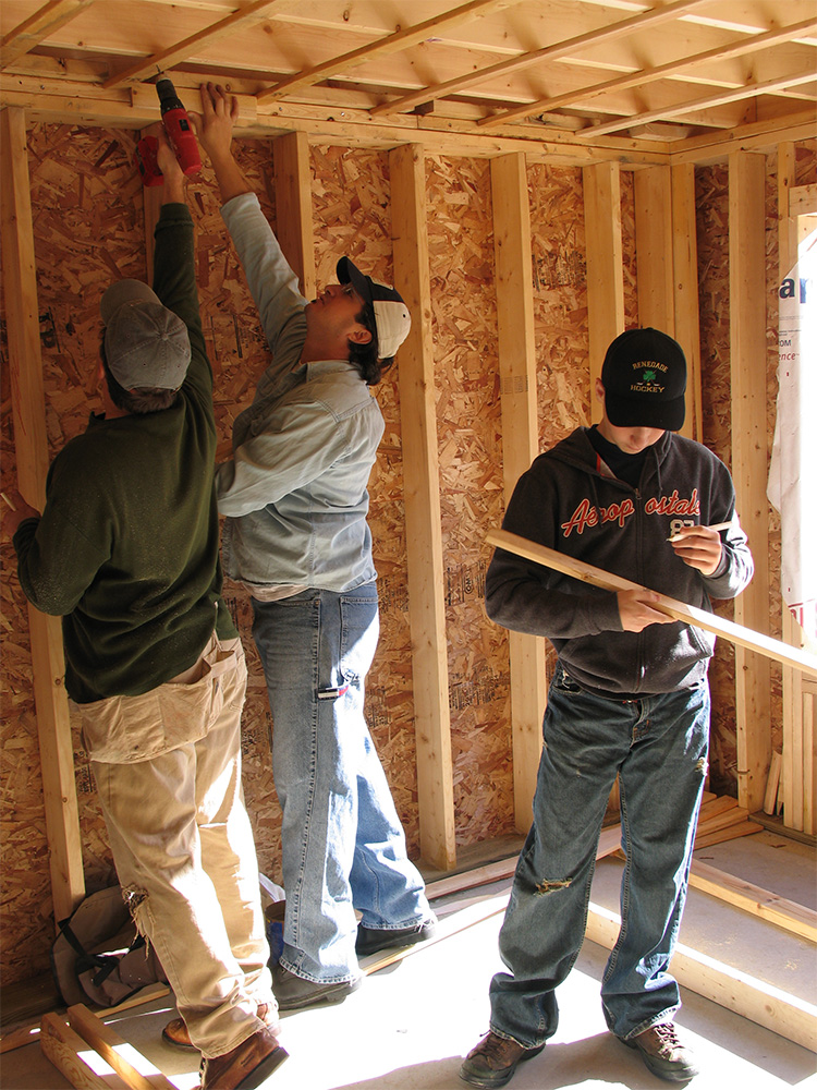Joe Ferolito's son, Joe, and a man in a blue shirt, hammering away at the wooden wall