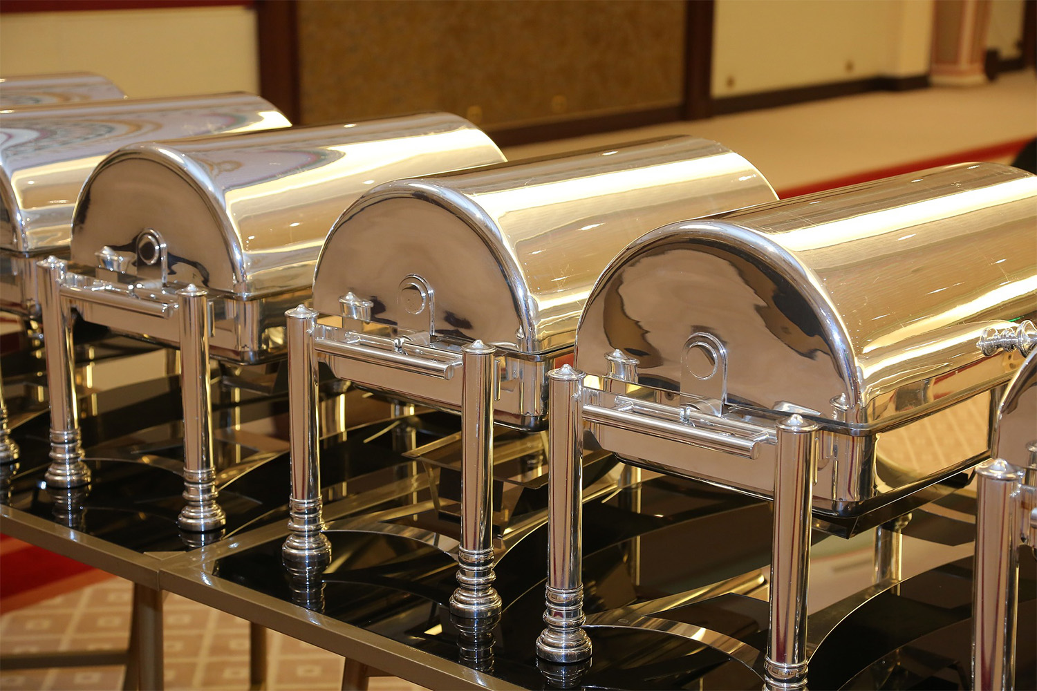 Long table with silver buffet food trays lined up 