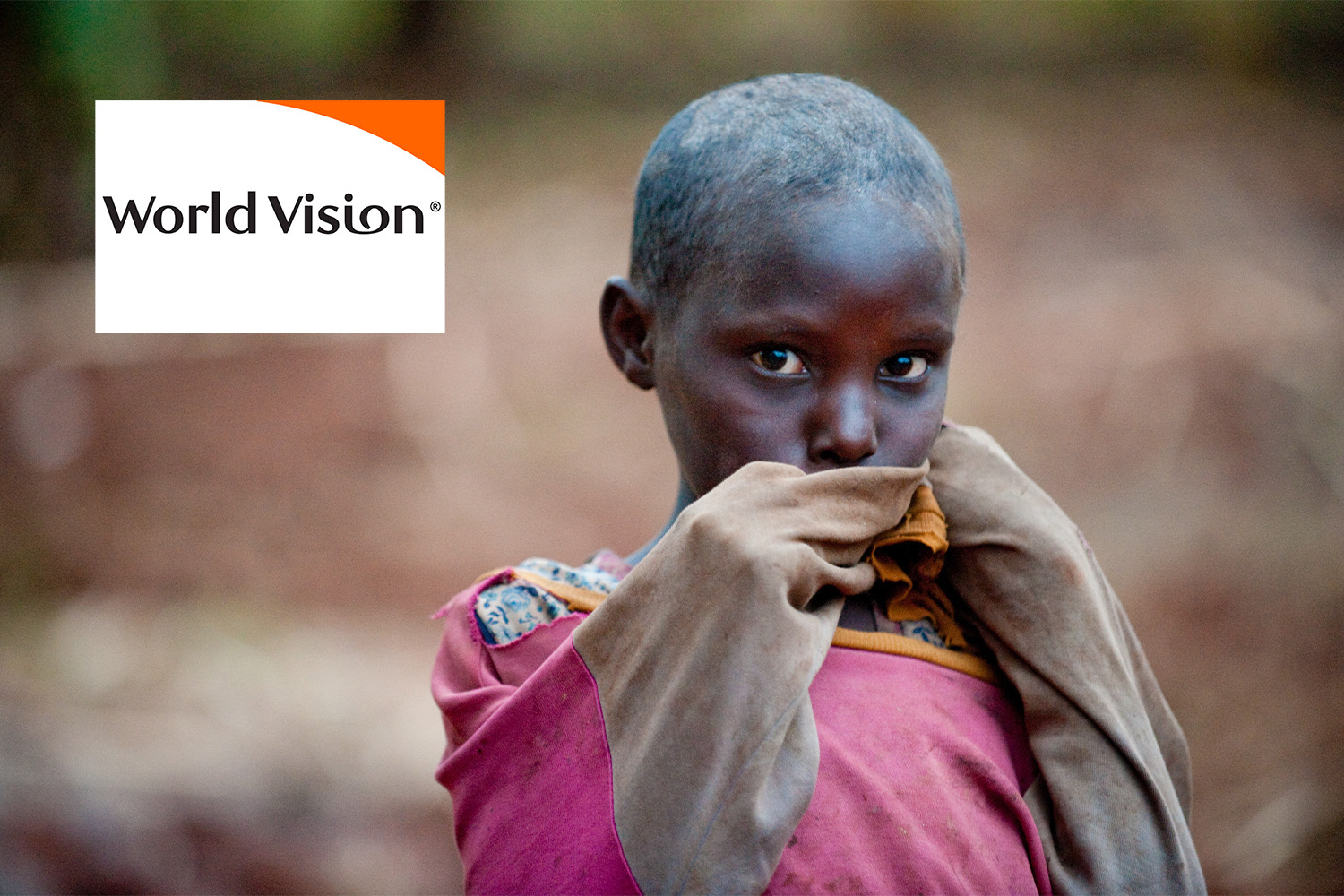 African child wearing a pink jacket, "World Vision" logo at top left corner 
