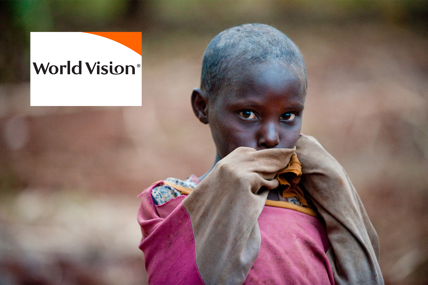 African child wearing a pink jacket, "World Vision" logo at top left corner
