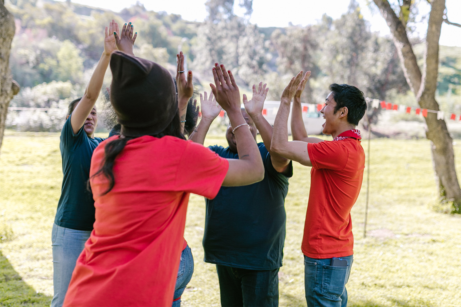 community service volunteers wearing red shirts, and doing a high five 