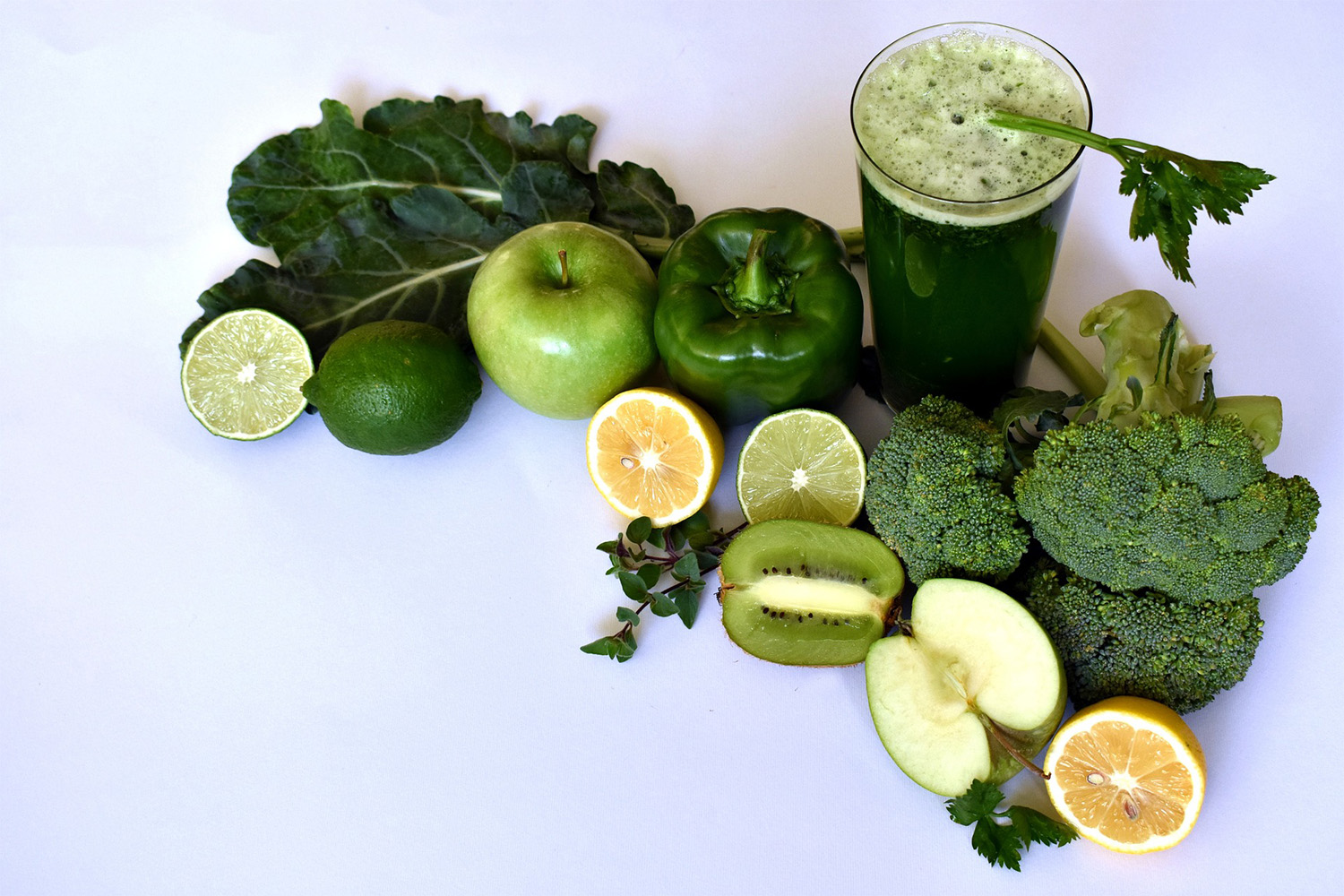 green smoothie with ingredients laying next to it 