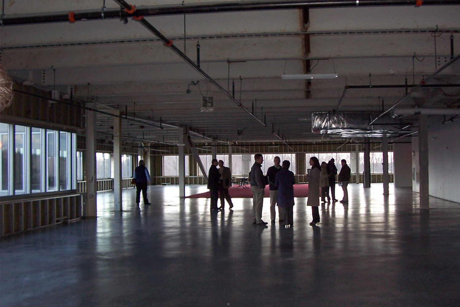 TOCCI's Planning and Cost Engineering team visit site for a project walkthrough. A group of people stand in a circle in discussion.