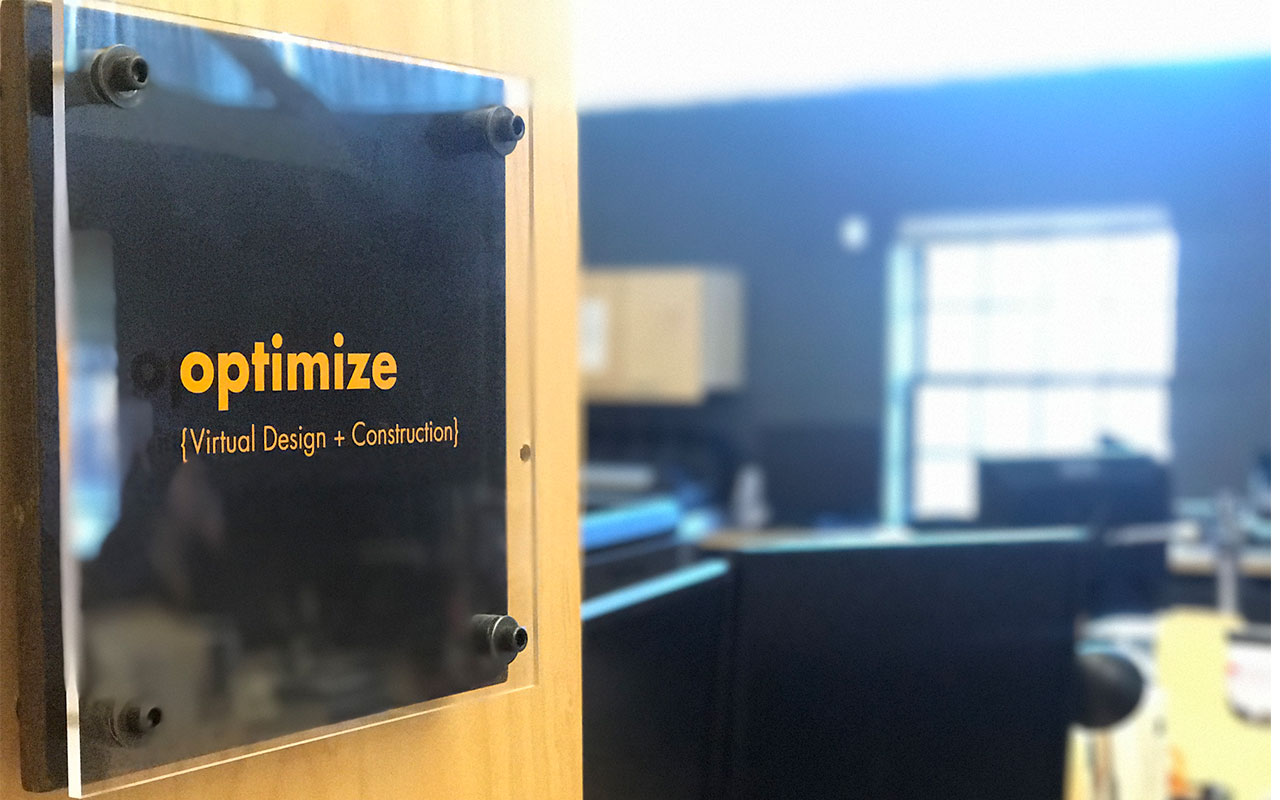 Image of office wall plaque in the VDC department, inscribed with the word "Optimize"
