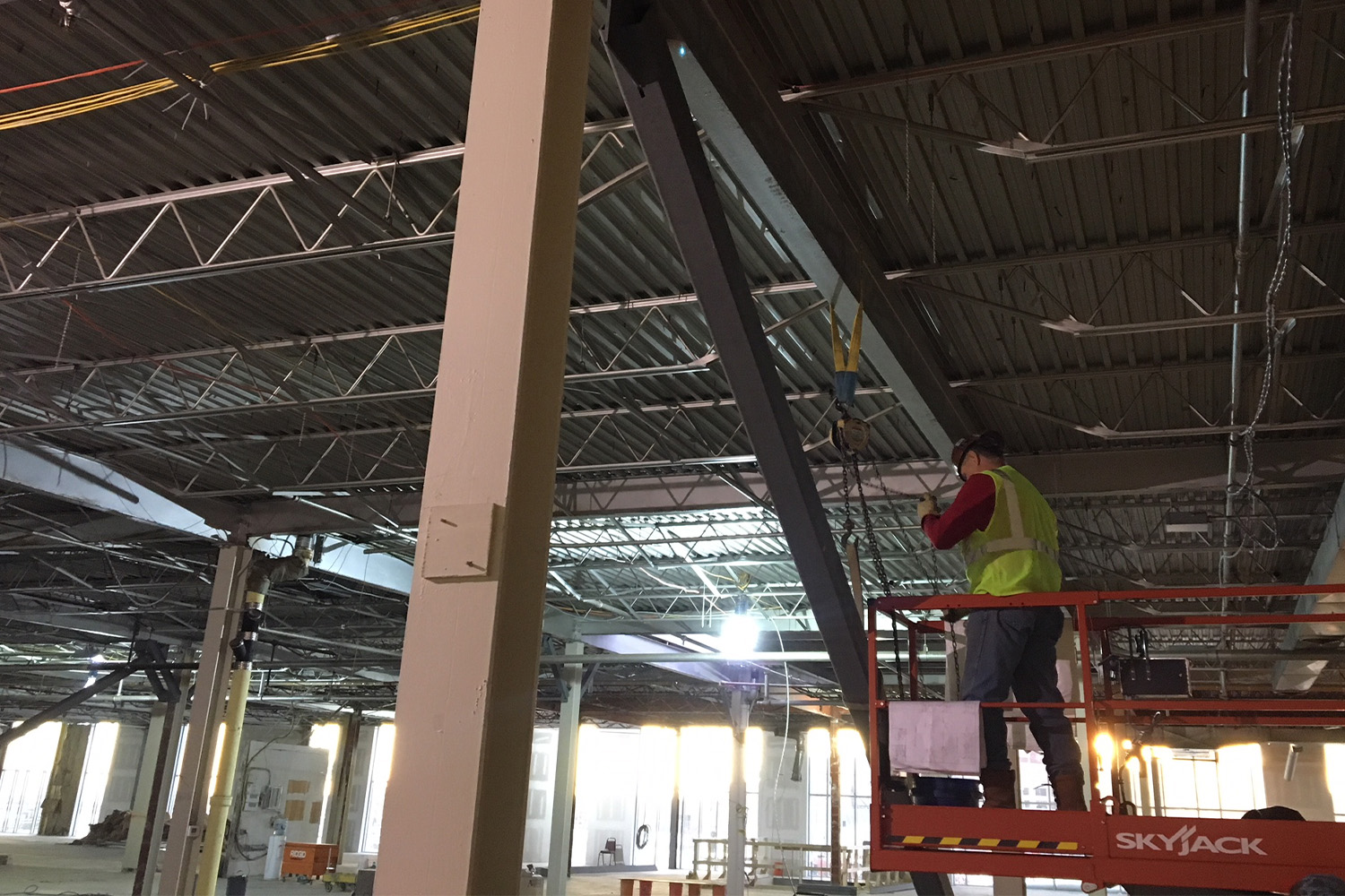 Construction work stands on a skyjack, or scissor lift, as he works beneath steel beams at 645 Summer Street.