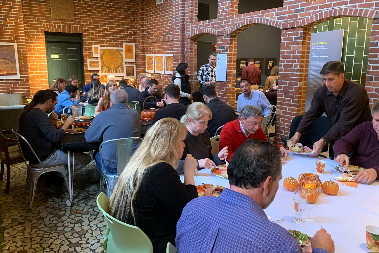 Tocci staff eat a Thanksgiving meal after donating to the Woburn Council for Social Concern. They sit at tables in Tocci's front lobby.