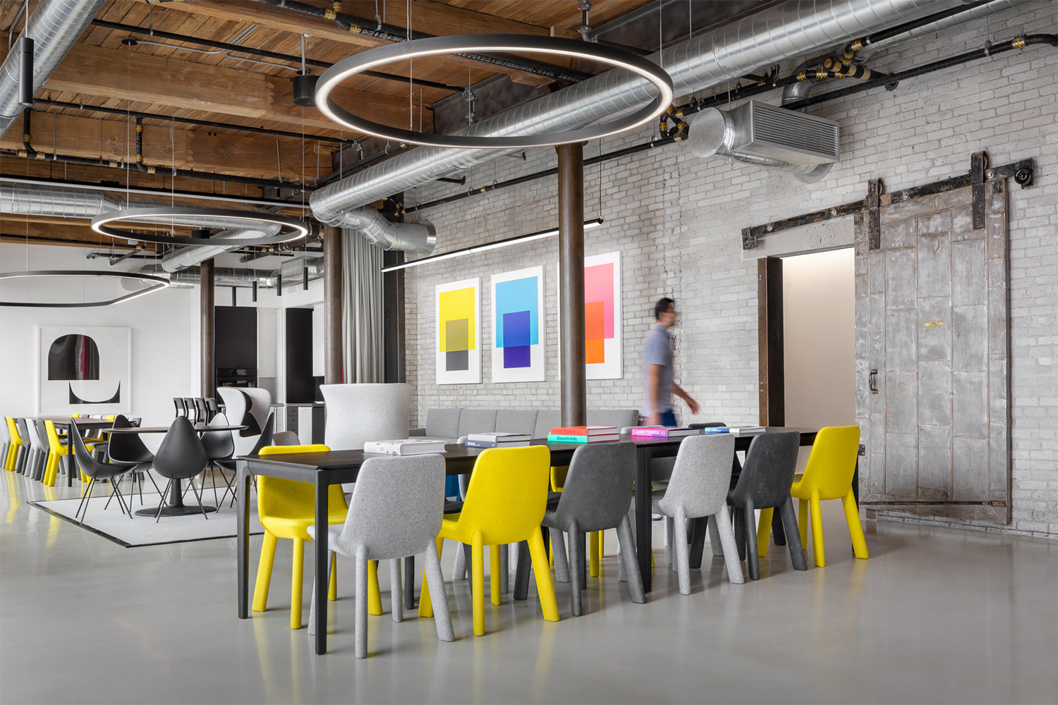 Lobby area with fun modern chairs and tables, hanging circular light fixtures, and a wooden ceiling