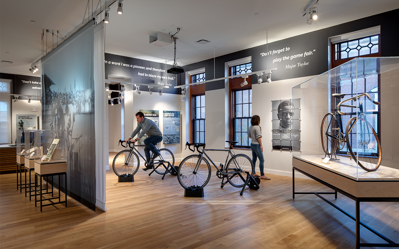 2 people observing bicycle exhibit's at the Major Taylor Museum 