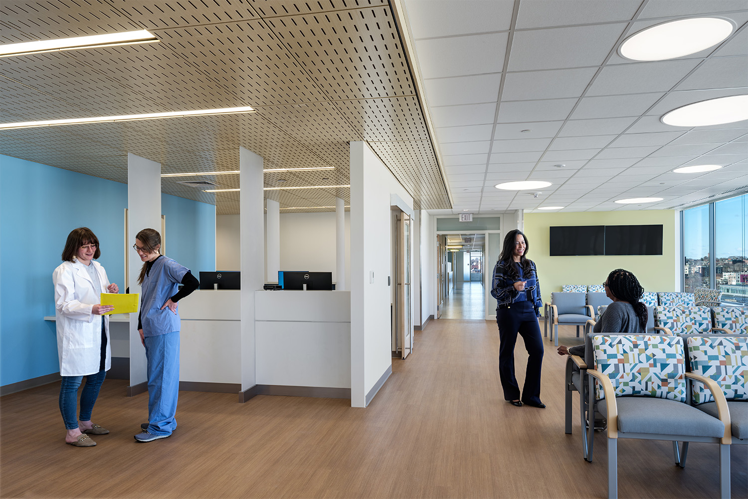 Outpatient pediatrics hospital floor, with a nurse and doctor in discussion near the front desk
