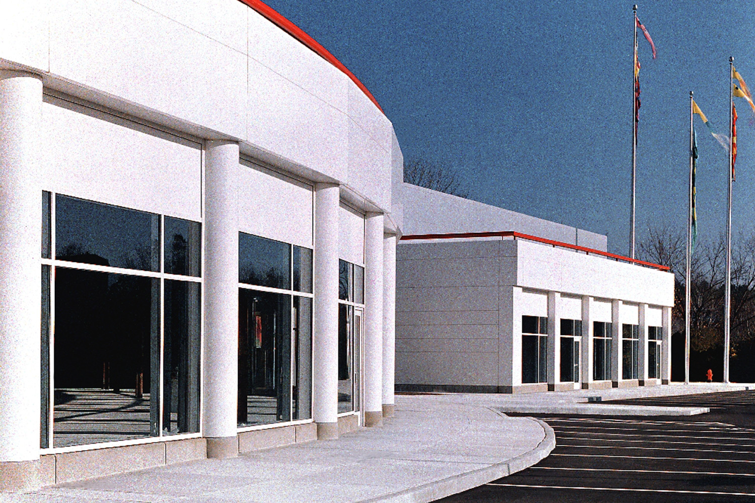 Flag poles next to building exterior with rounded walls