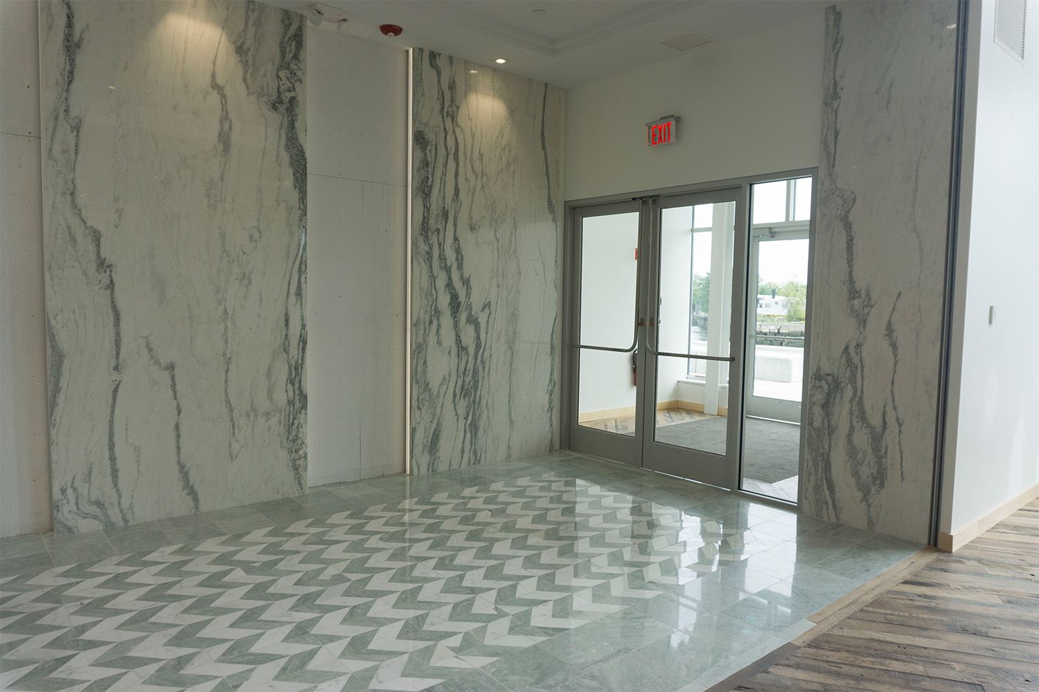 Reception room with white marble walls and floor with arrow-pattern design