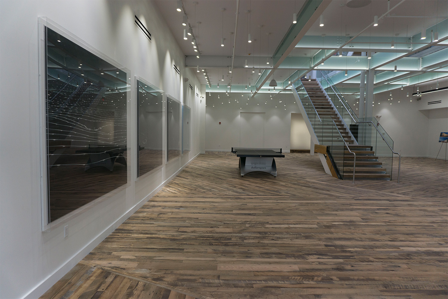 Lobby area with windows on ceiling, wooden flooring, next to stairwell 