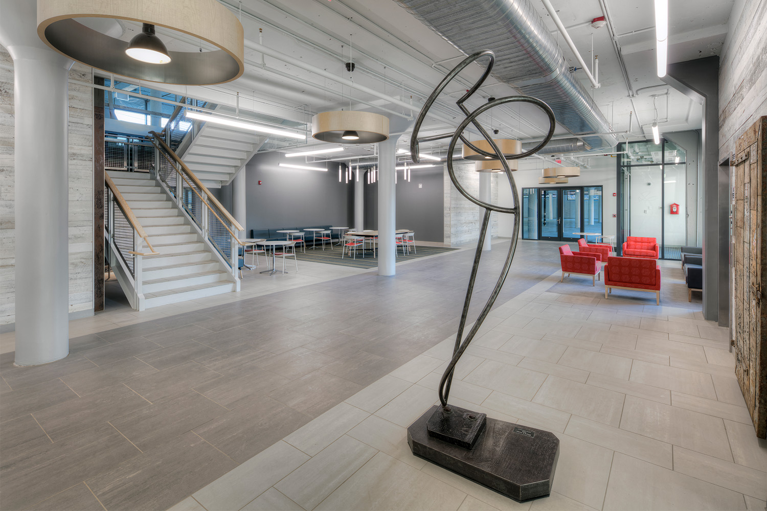 View of lobby from  entrance: modern art piece in the front, red couches to the right, and staircase to the left 