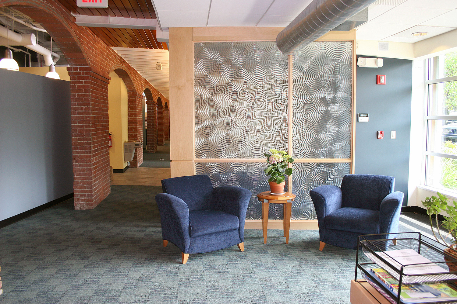 Lobby area with artful glass wall and plush blue chair seating 