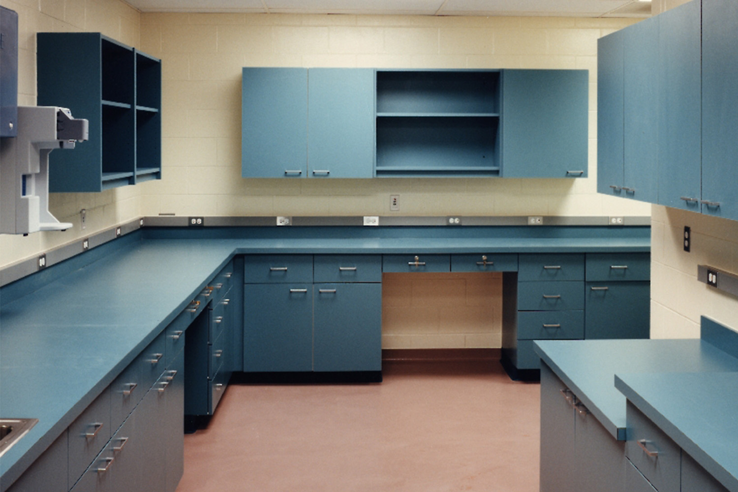 Clean medical exam room with blue counters and cabinets