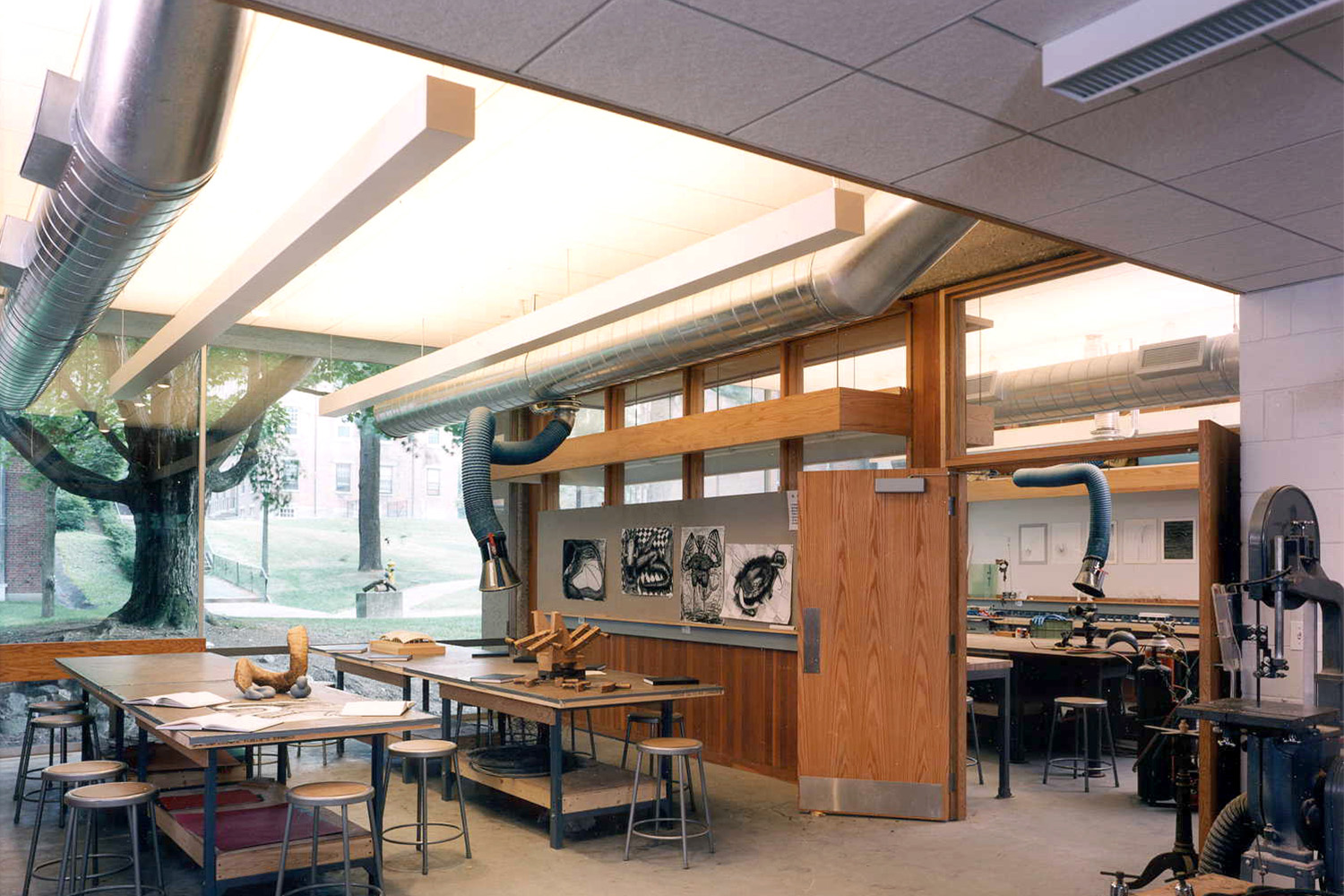 Workshop with long wooden tables, chairs, and windows allowing ample light into the room 