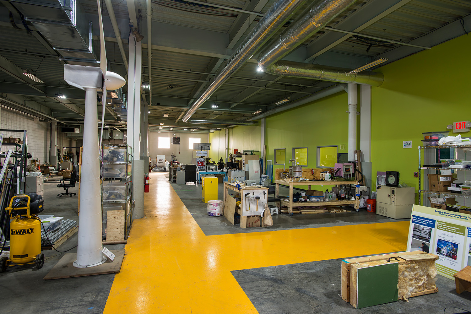 Laboratory with yellow pathway painted on floor, and exposed metal beams on ceiling 