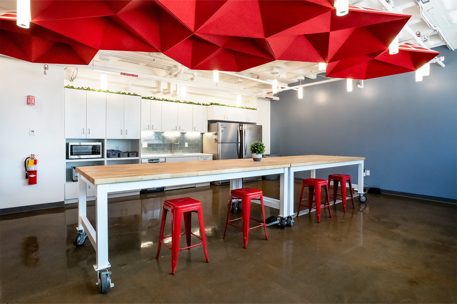 Kitchen with amenities, and modern red geometric ceiling design to match with red chairs