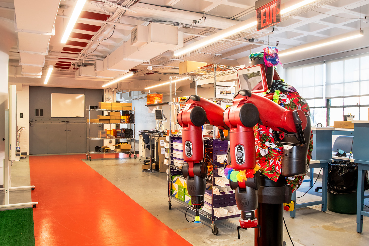 Rows of robots next to orange pathway on floor, in robotics lab 