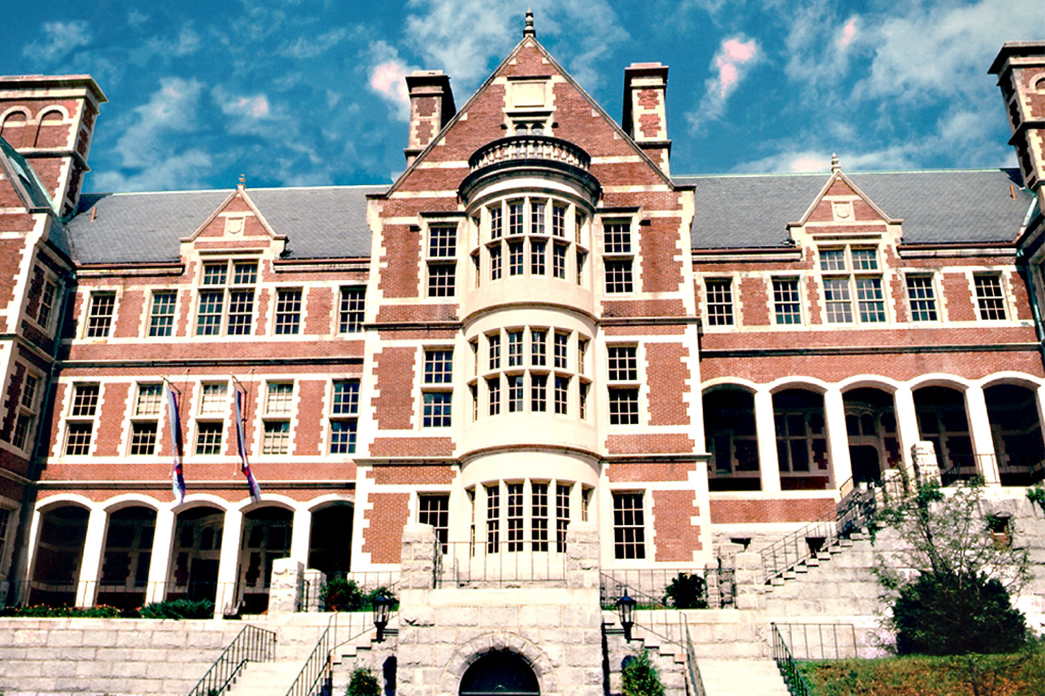 Front exterior of red brick building with arches and pillars on bottom