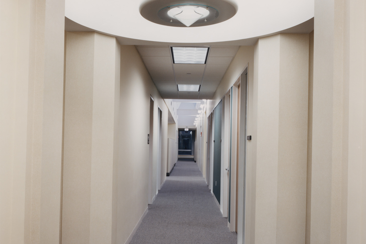 Hallway with bathroom to the left, doors to the right, and building exist at the end of the hall 