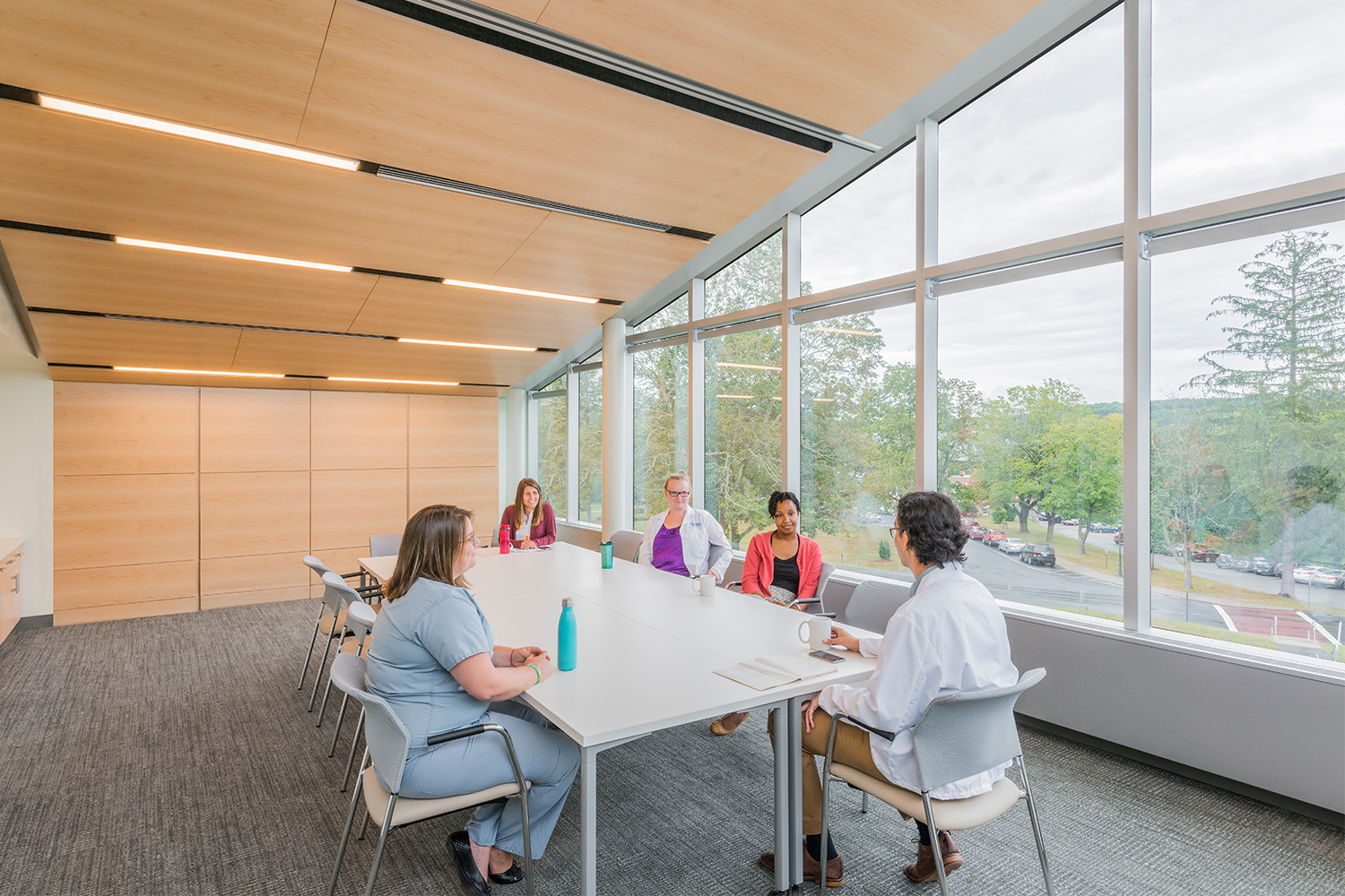 People talking in conference room, with enormous window on wall for ample light