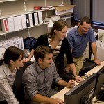 4 people working behind computer 