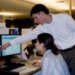 man directing woman to something on computer screen 