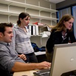 3 people working next to computer 