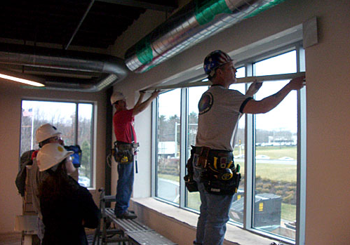 2 construction workers measuring length of window