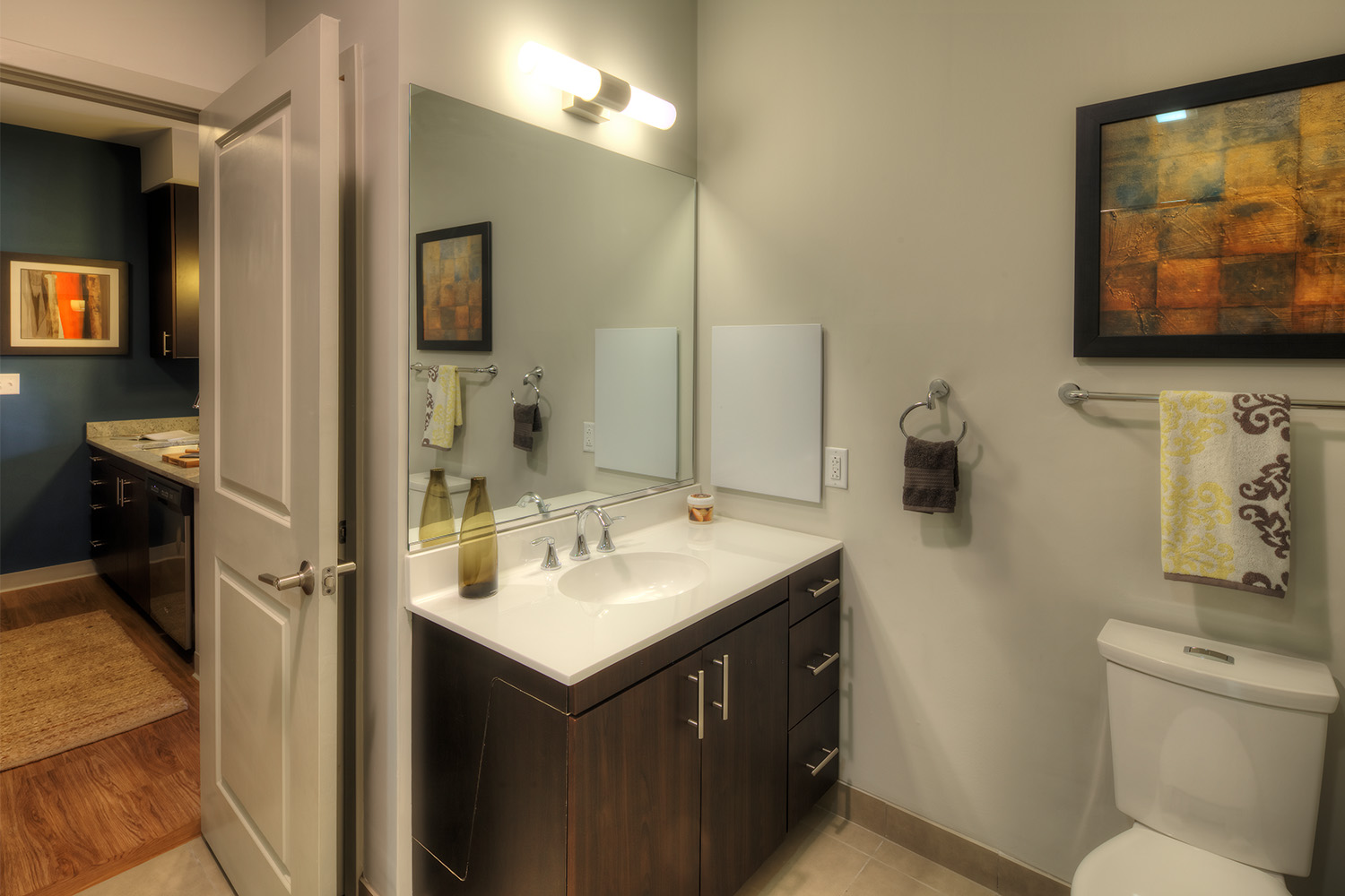 White bathroom with sink, and painting mounted to wall 