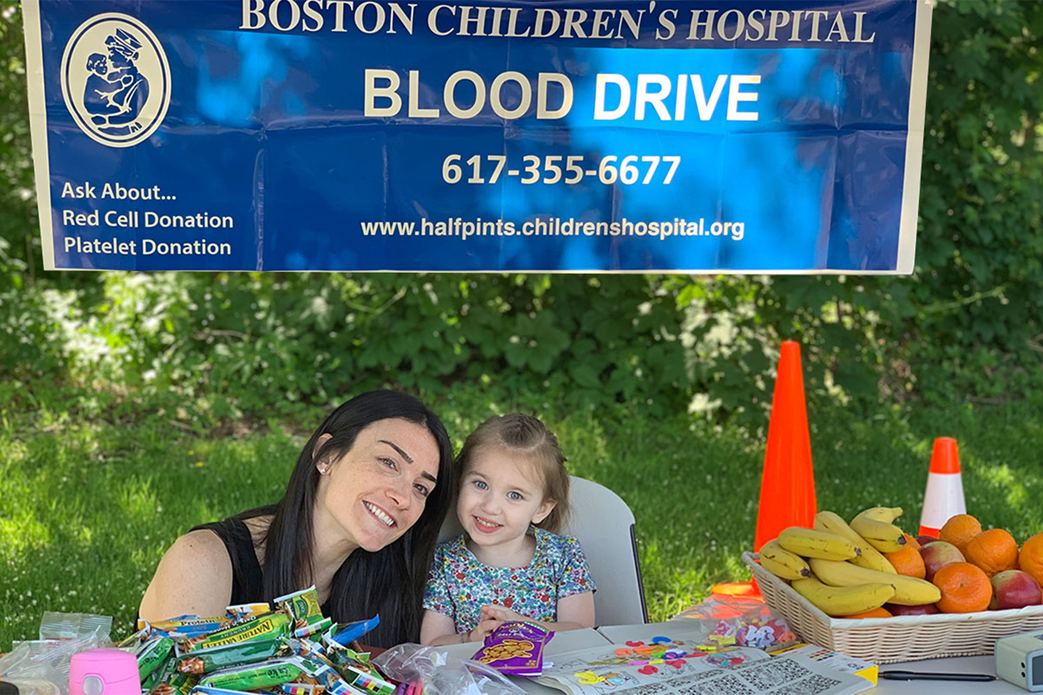 Katie from Tocci, and Mia sitting by booth for Blood Drive 