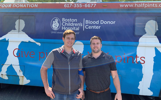 2 men standing by blood donation bus 