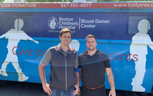 2 men standing by blood donation bus