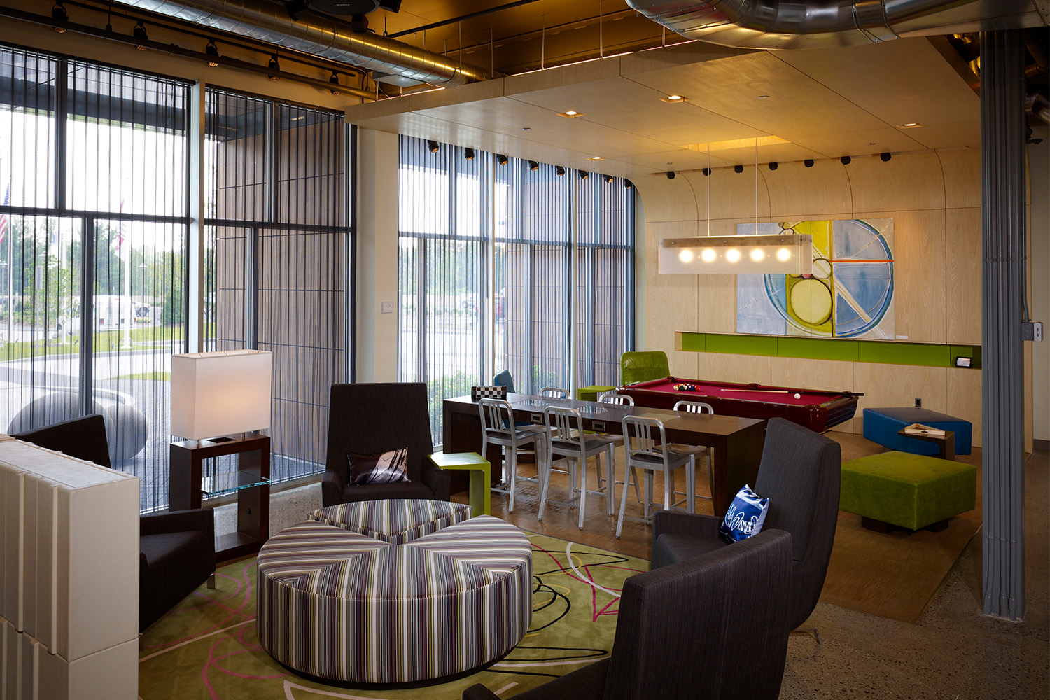 Lounge area with pool table, large draped windows, and plush seating 