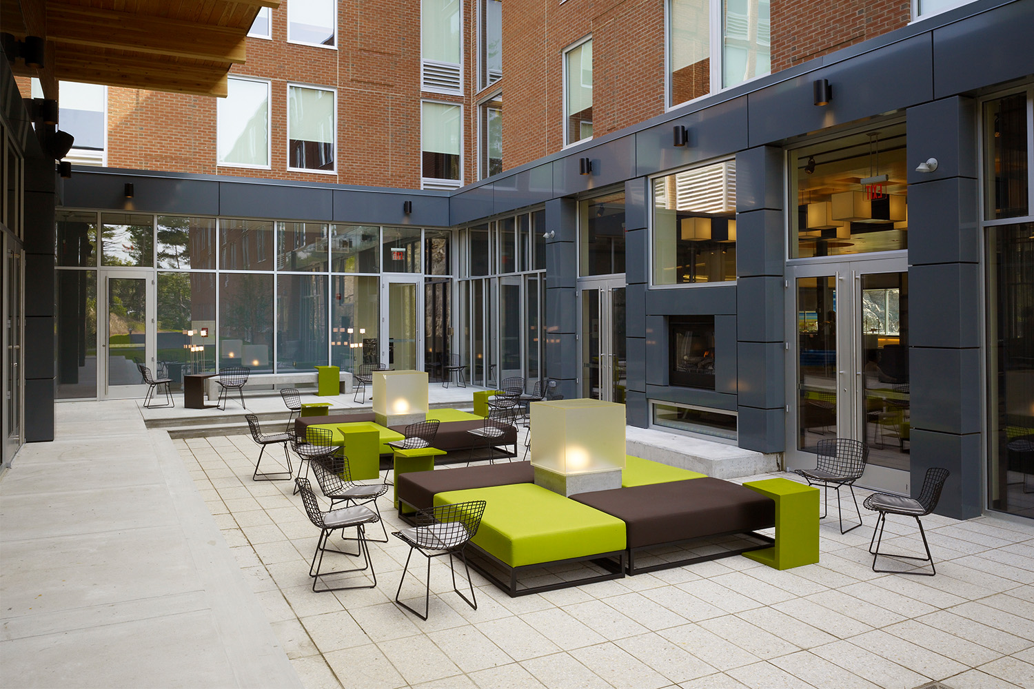 Outdoor patio area with black metal chairs, and green and brown cushions 