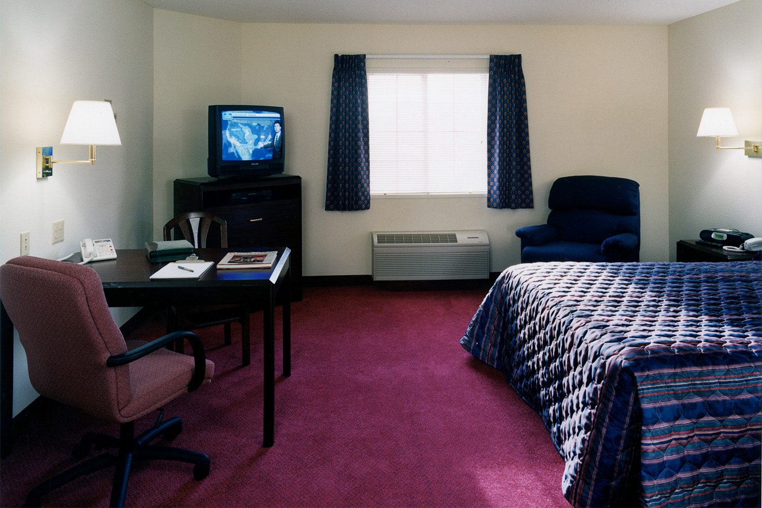 Bedroom with plush red carpeting and small window