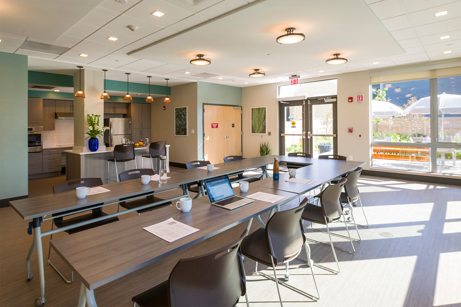 Café & Conference room with ample seating and lighting, with a partial kitchen 