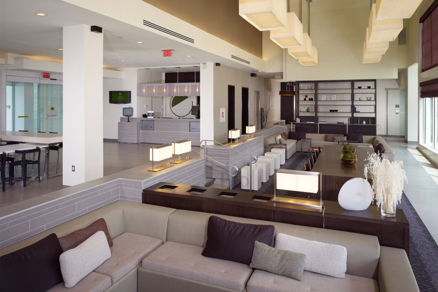 Lobby with tan couches and, rectangular light fixtures, and large windows 