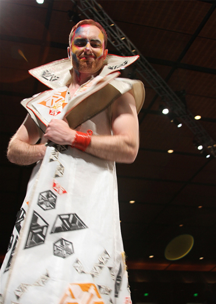 Male model in white coat posing at end of runway 