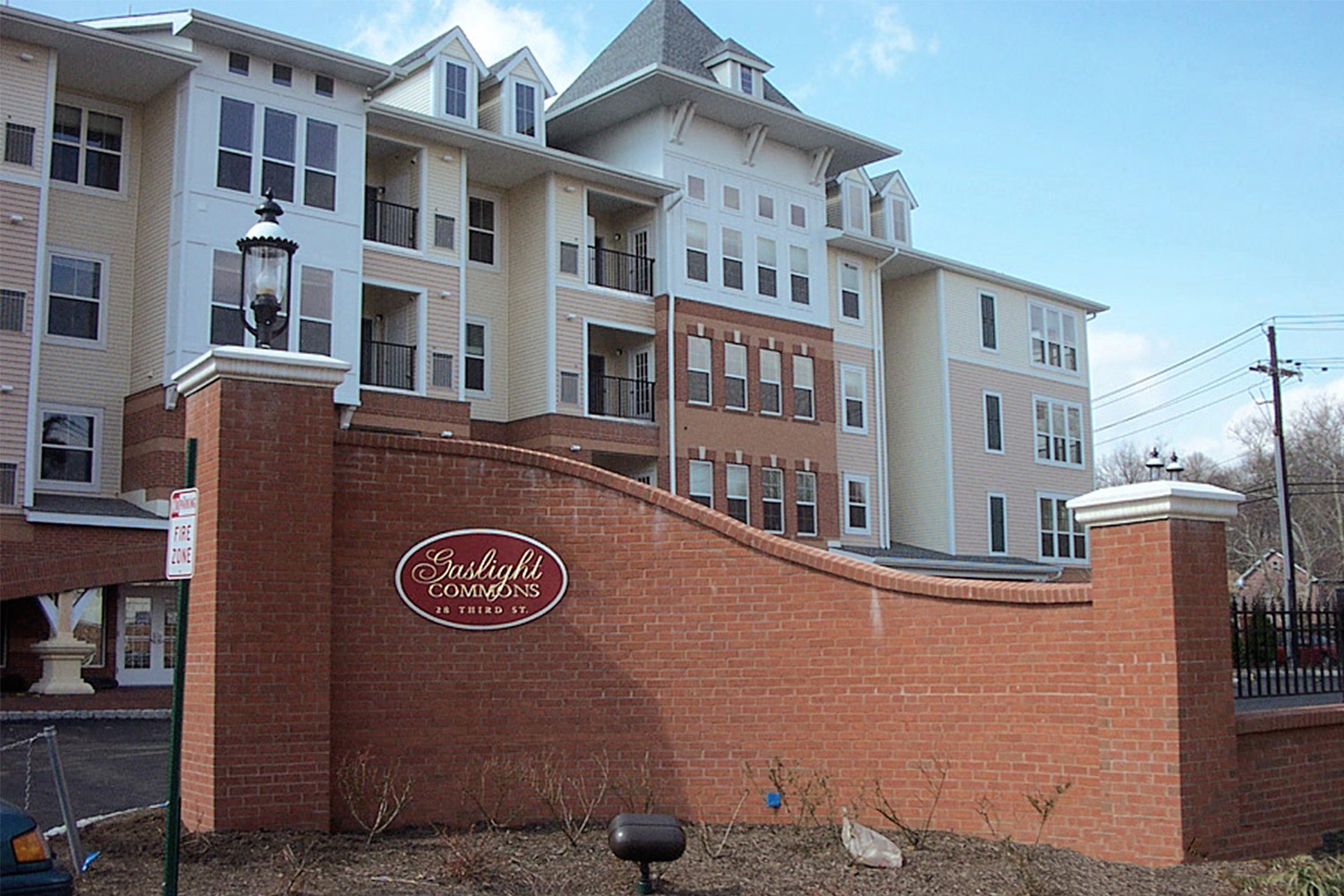 Large redbrick sign with "Gaslight Commons" written in cursive at the entrance