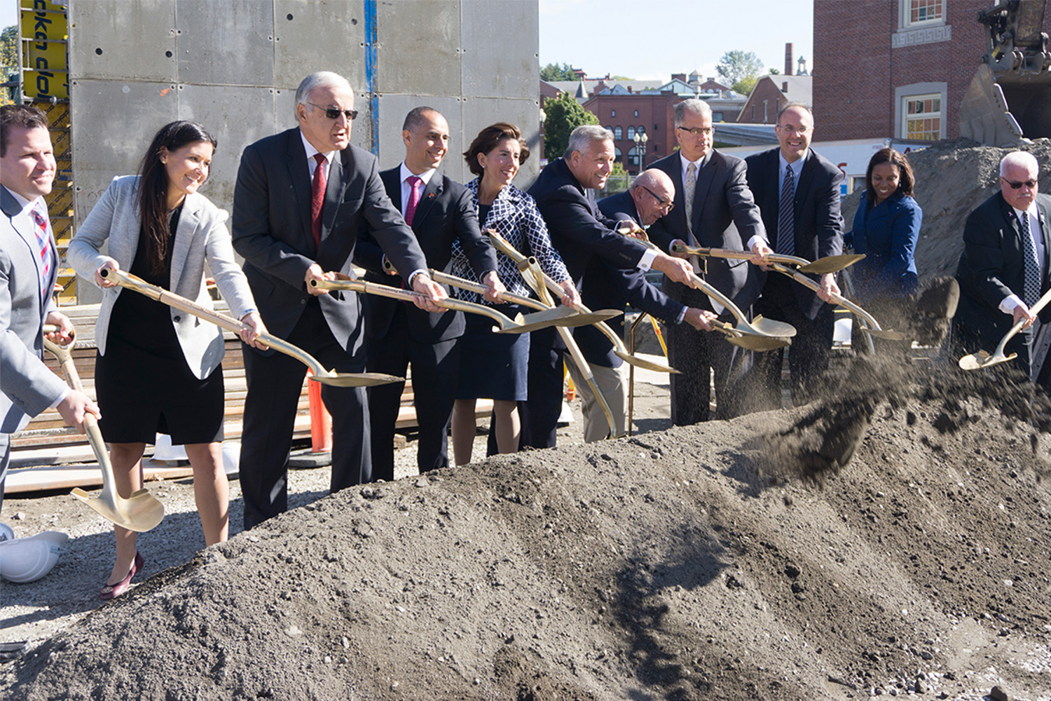 Corporate workers shoveling dirt in front of new hotel