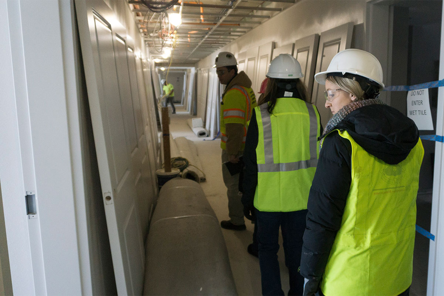 3 construction workers walking down hallway