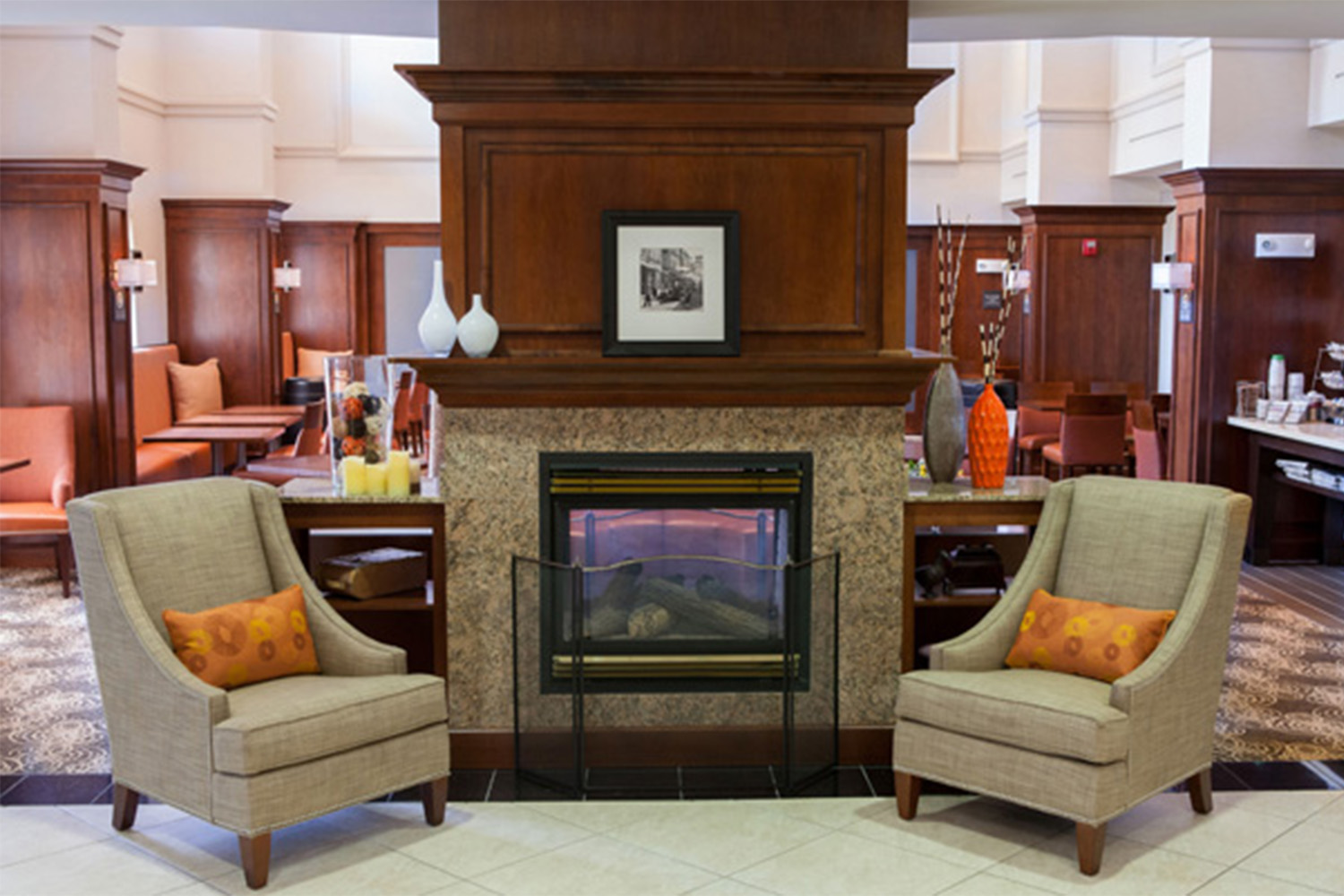 lobby area with 2 tan plush lined chairs, and fireplace 