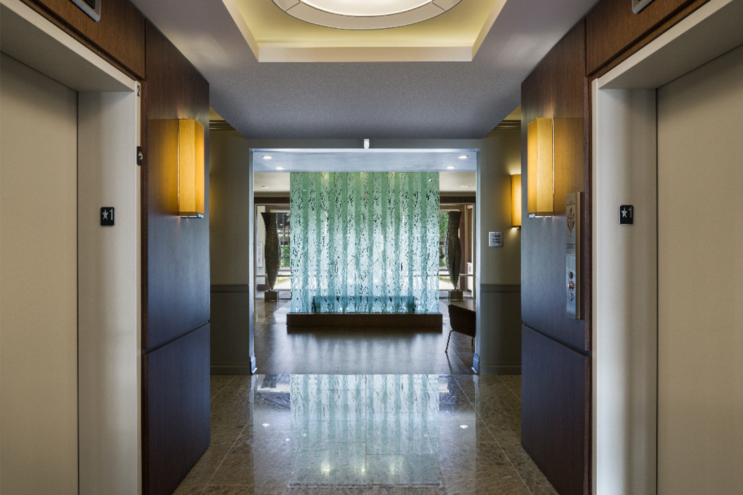 Hallway with an elevator on both sides, and modern light sconces 