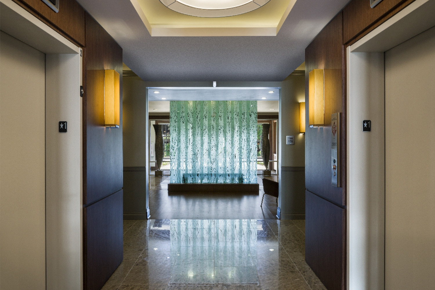 Hallway with an elevator on both sides, and modern light sconces