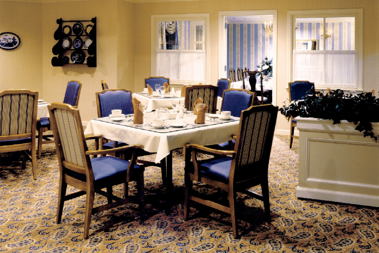 Quaint dining room with double windows and wooden chairs 