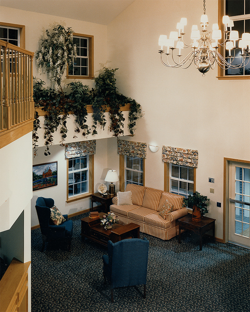 Elevated view of lobby/. Lobby has seating, planters, and hanging chandelier