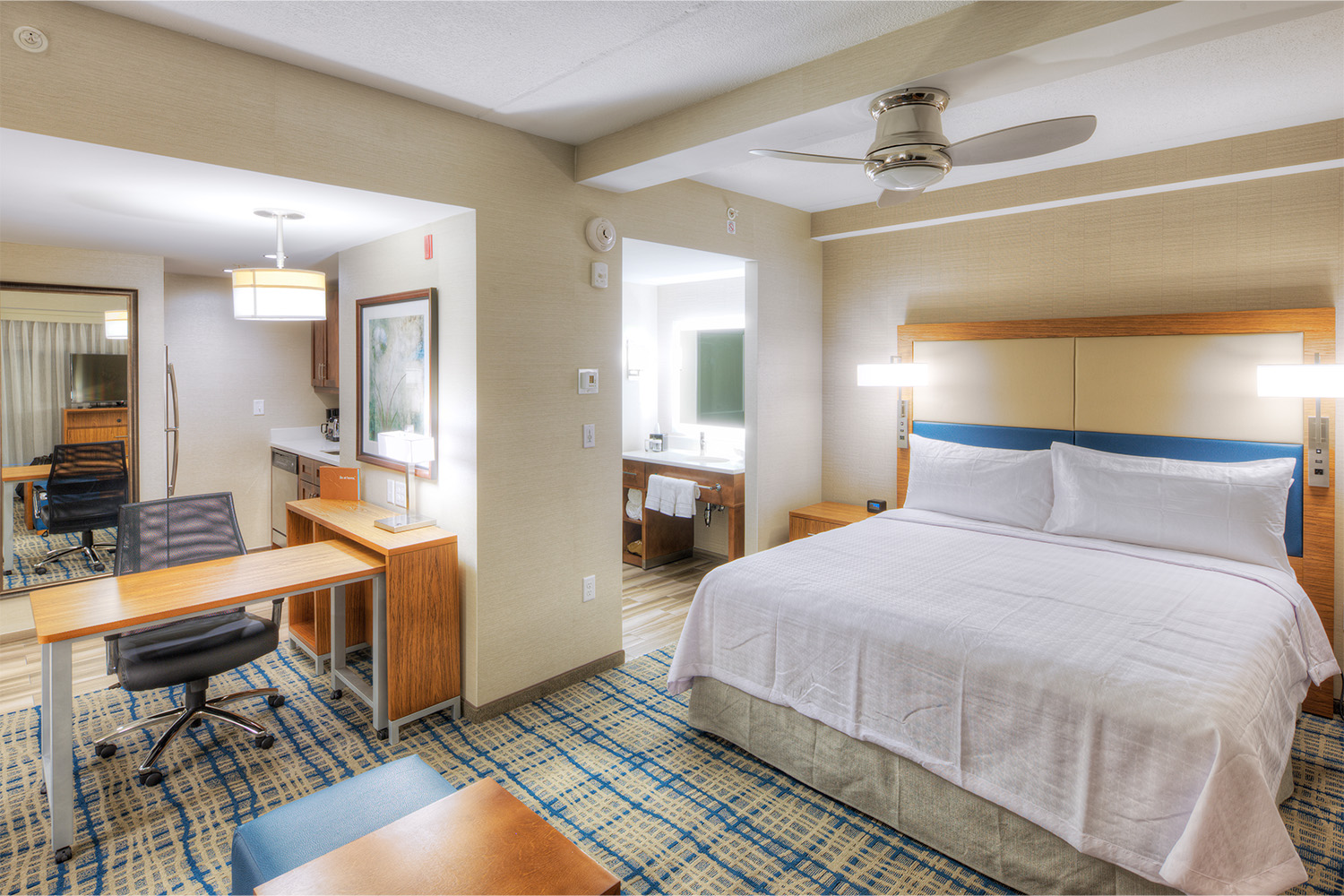 Single-suite room with plush bed, clean bathroom, and desk area 