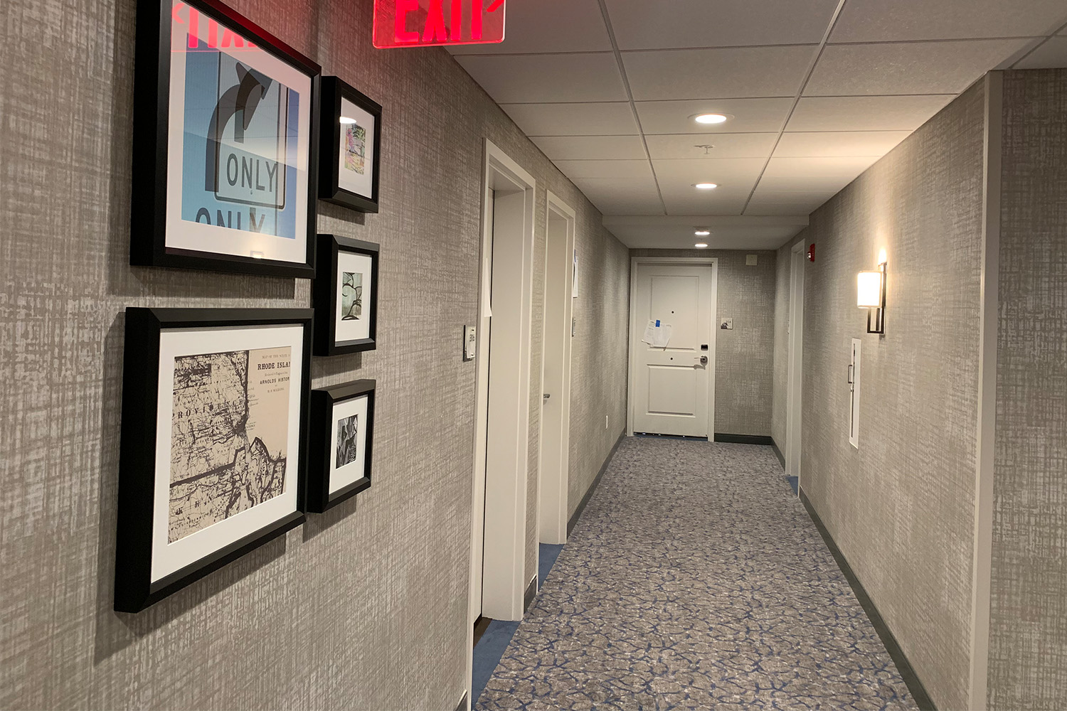 Unoccupied hallway with 2 doors to the left, and roadmap art on the wall 